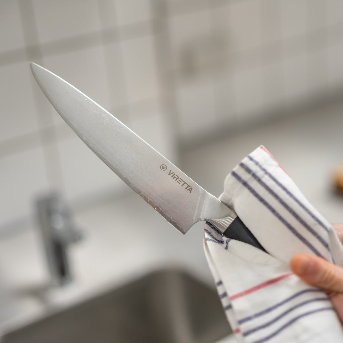 En Shōjin Aira kokkekniv tørres med et viskestykke ved køkkenvasken