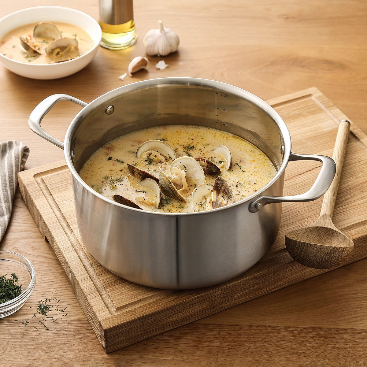 Cremet muslingesuppe i gryde i 3-Ply rustfrit stål på skærebræt