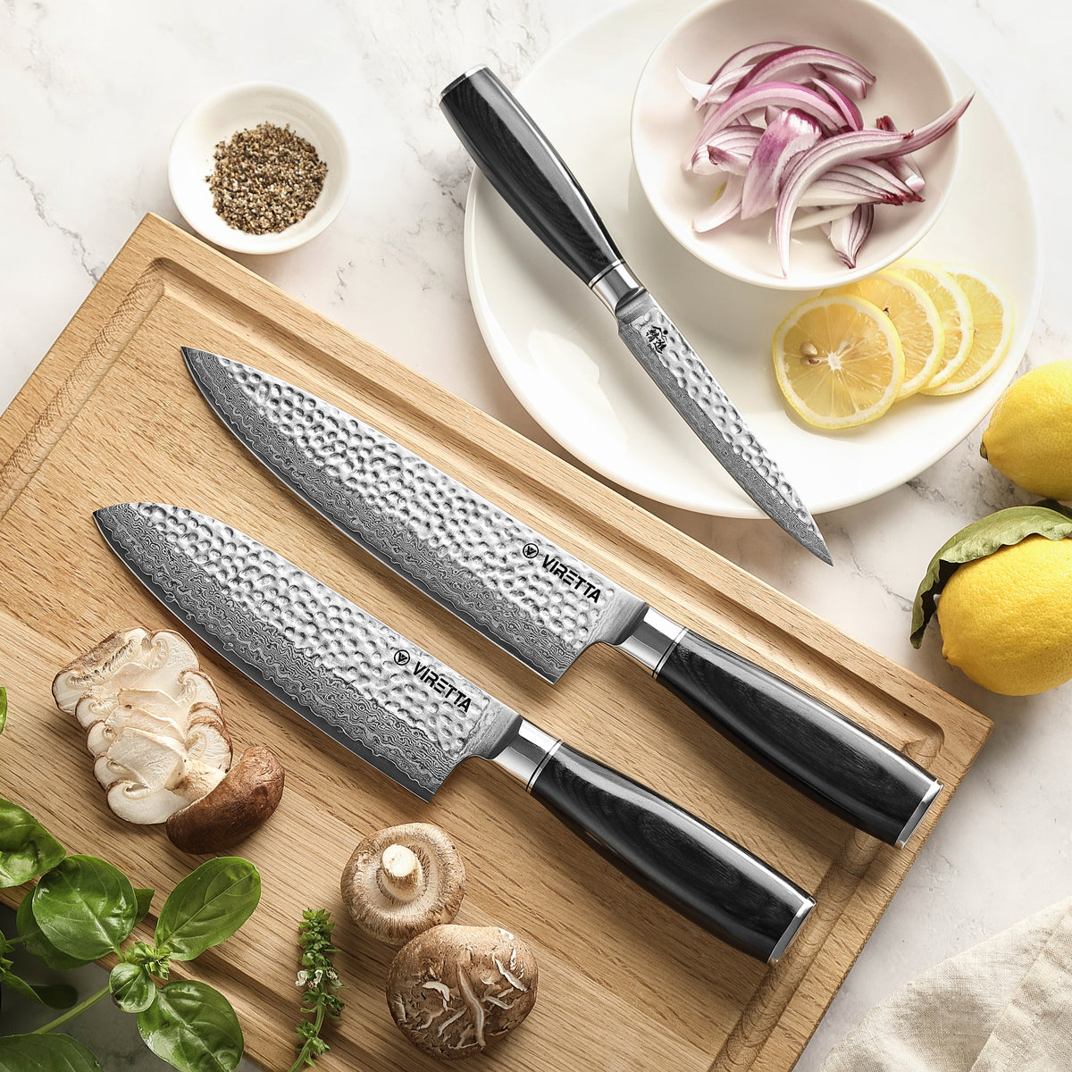Shōjin Taru kokkekniv og santokukniv på bræt i eg, universalkniv ved rødløg og citron