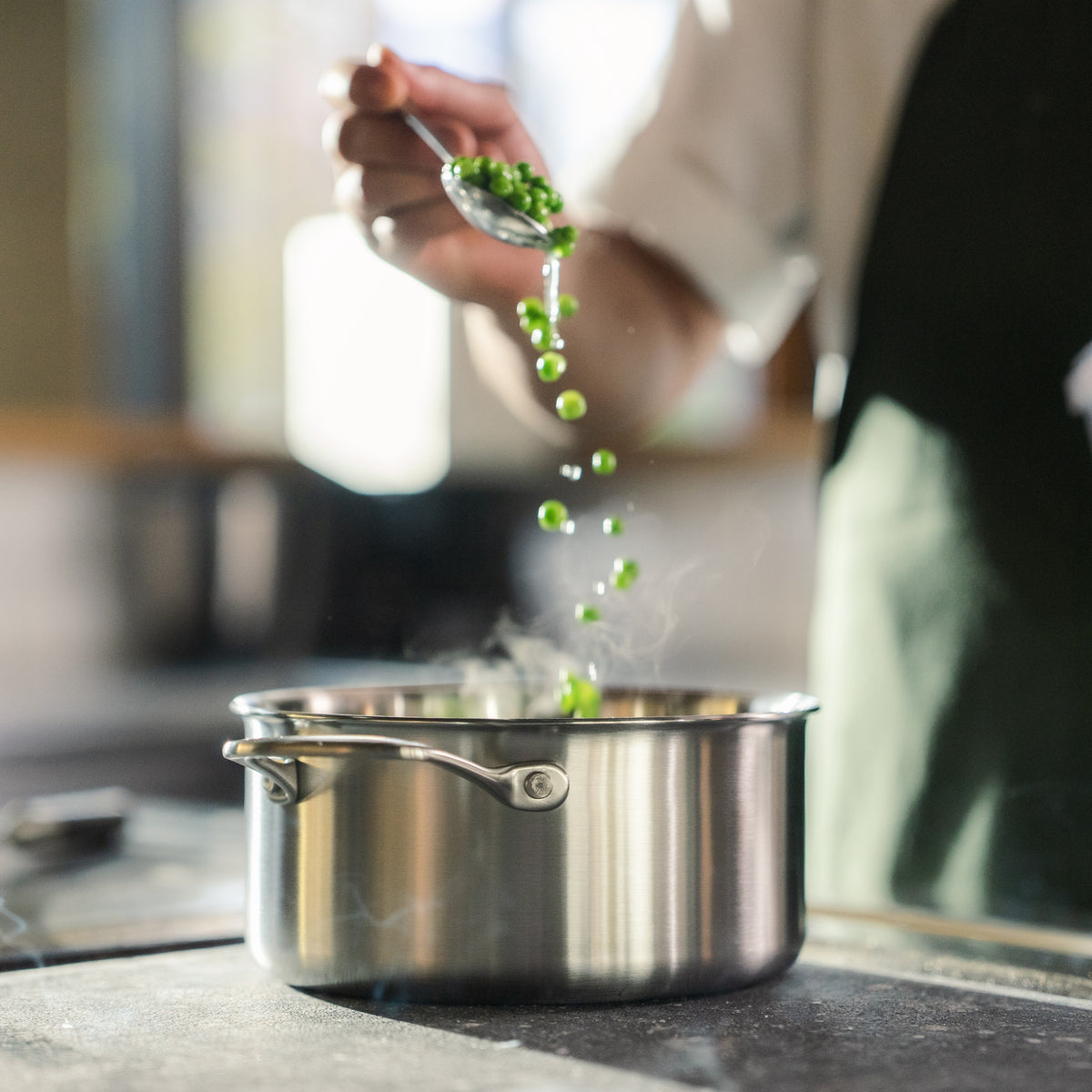 Ærter drysses i en dampende gryde i 3-Ply rustfrit stål i et professionelt køkken