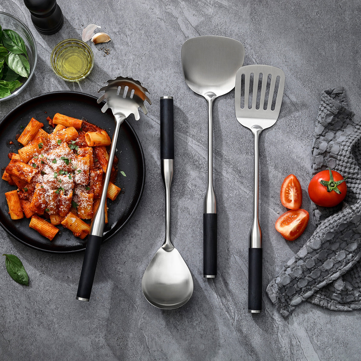Palet med huller, palet, pastaske og serveringsske med greb i G-10 ved en tallerken rigatoni med tomatsauce