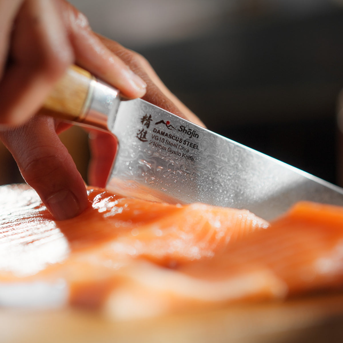 Laks skæres med en Shōjin Kaku gyuto med egetræsgreb, set tæt på