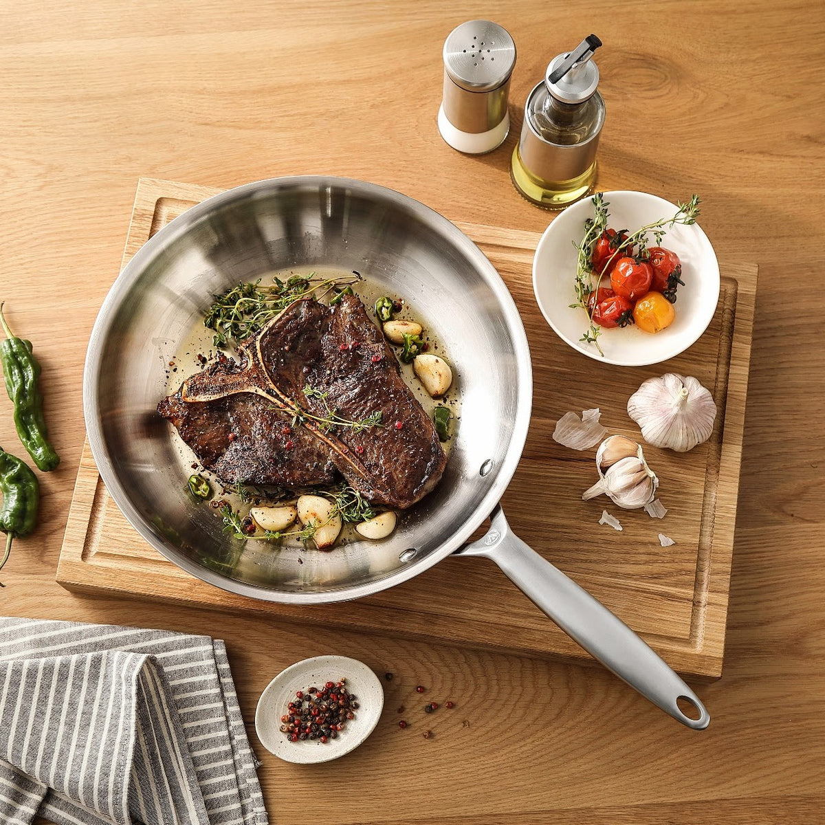 T-bone-steak med hvidløg i en stegepande i 3-Ply rustfrit stål på et skærebræt