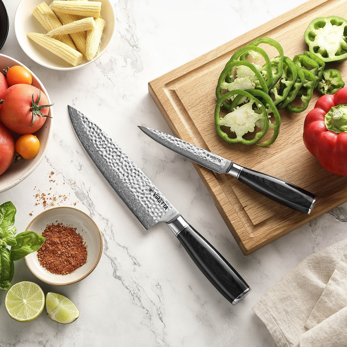 Shōjin Taru kokkekniv og universalkniv på marmor og bræt i eg med peberfrugt