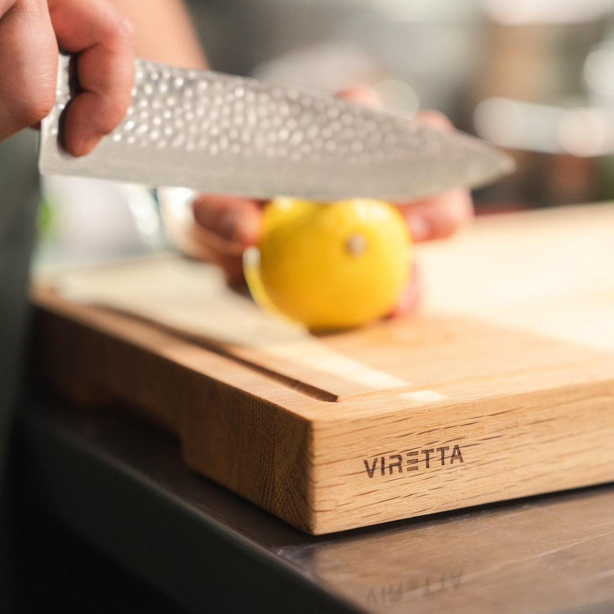 Citron skæres med en Shōjin Taru kokkekniv på et skærebræt i eg med saftrille