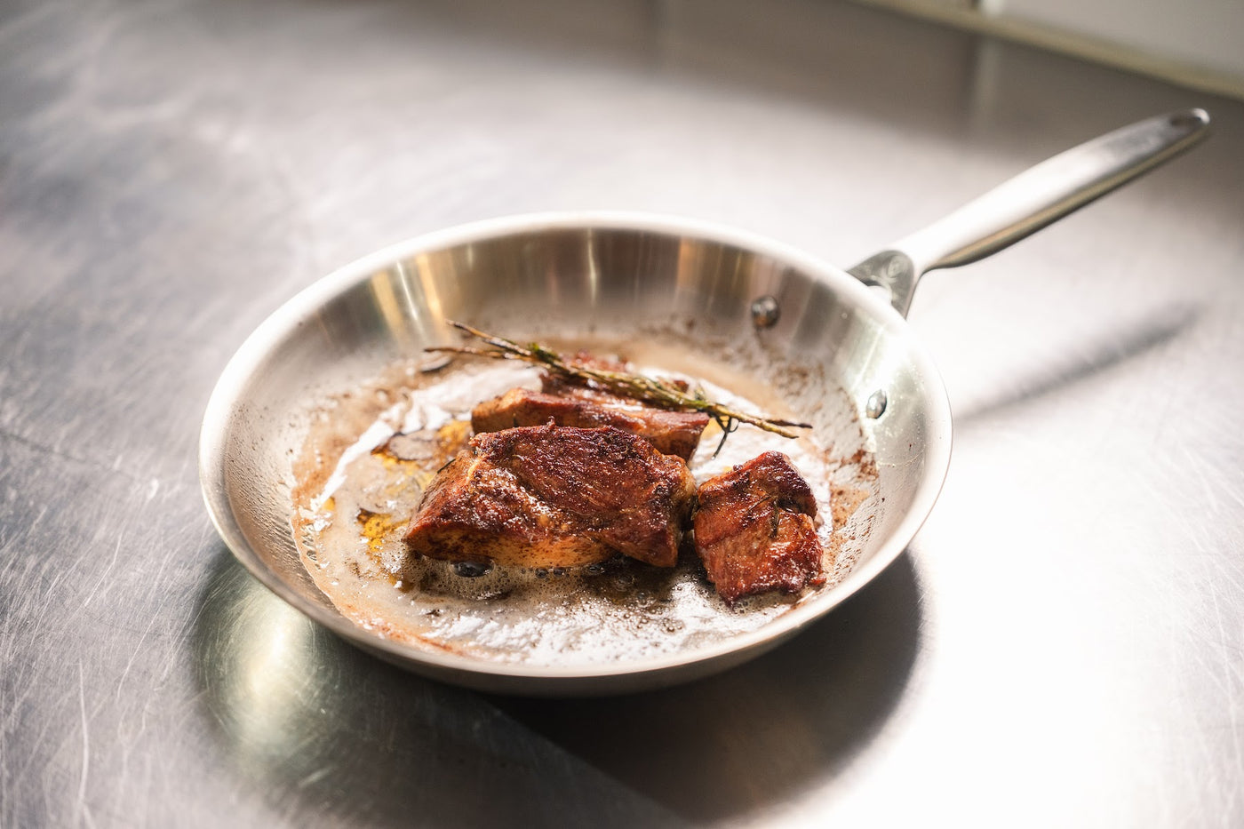 En bøf med rosmarin i en stegepande af rustfrit stål hos Bryggerens Spisekammer