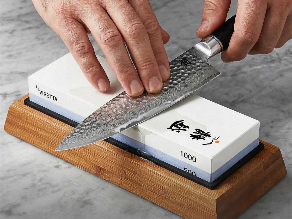 En kniv med hamret klinge slibes på en slibesten i en holder af træ