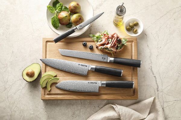 Shōjin Suna-knive på et bræt i eg med avocado, oliven og skinke