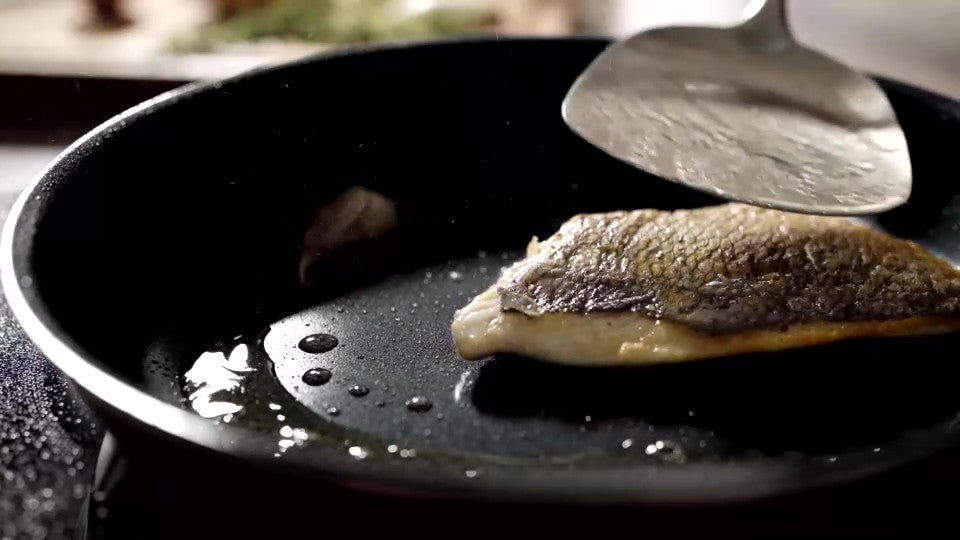 Et stykke fisk lægges på en pande i Titanium Plasma og vendes med en palet i metal